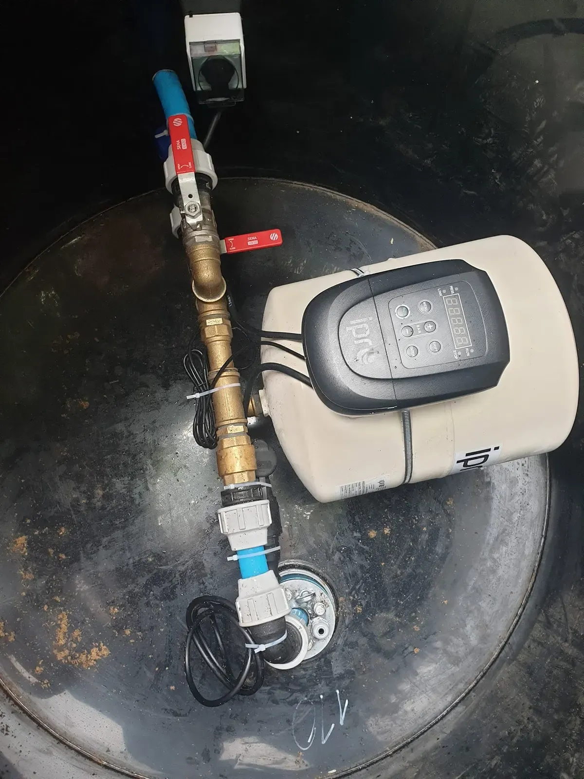 Wnętrze obudowy studni głębinowej: zawory, zbiornik hydroforowy i elektroniczny sterownik pompy