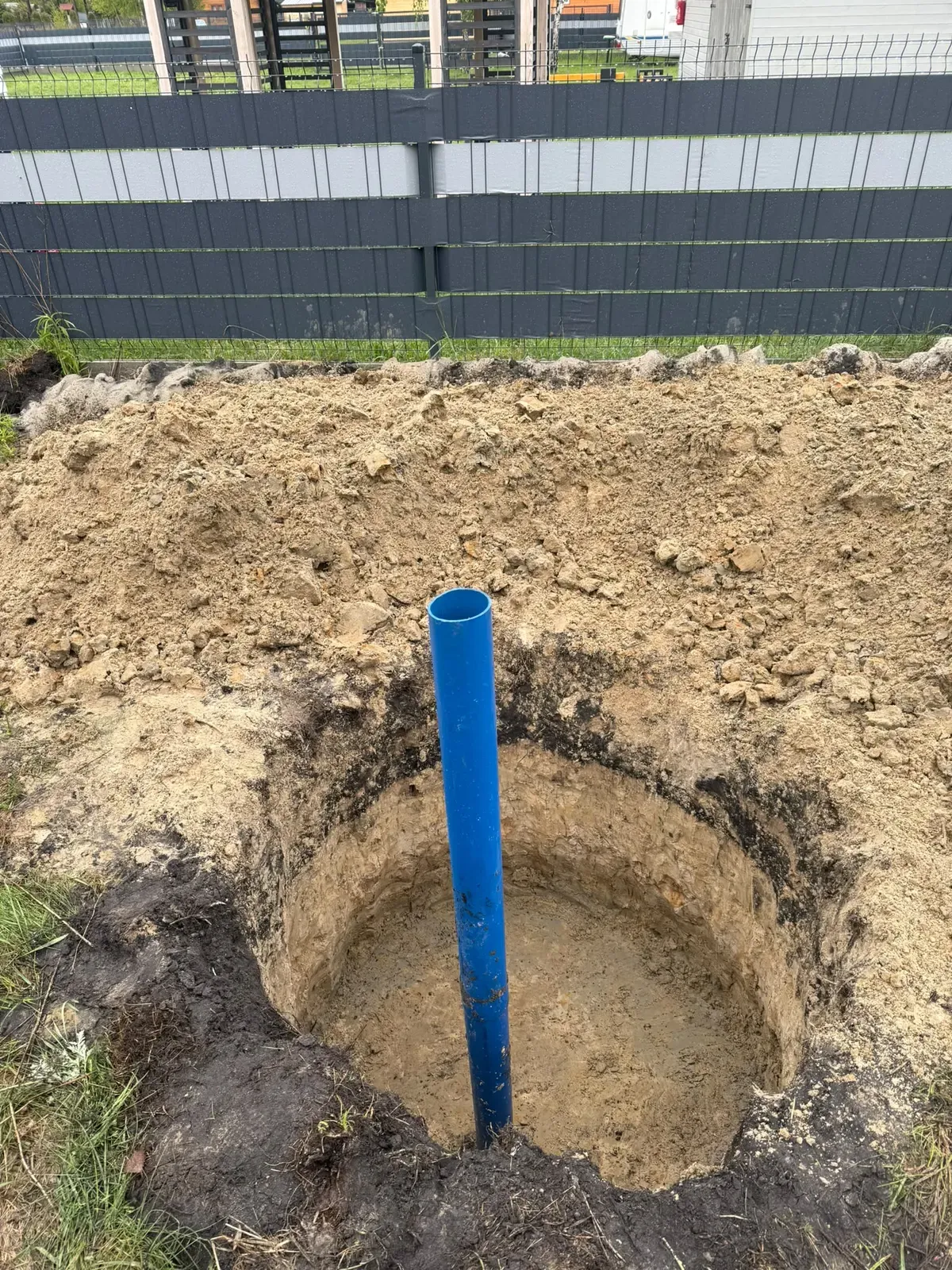 Niebieska rura studni głębinowej wystająca z piaszczystego wykopu
